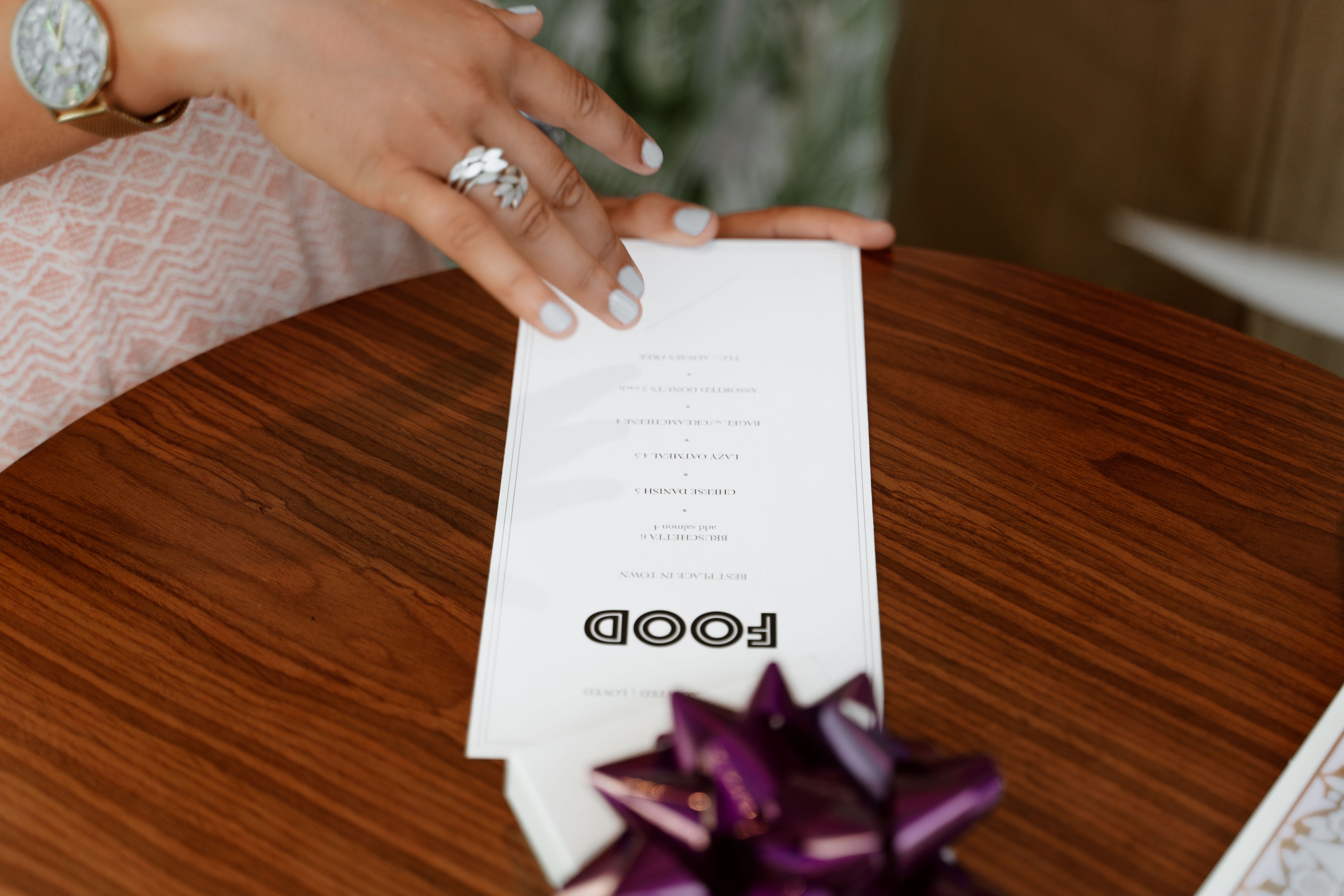 Hand holding a restaurant menu over a wooden dining table